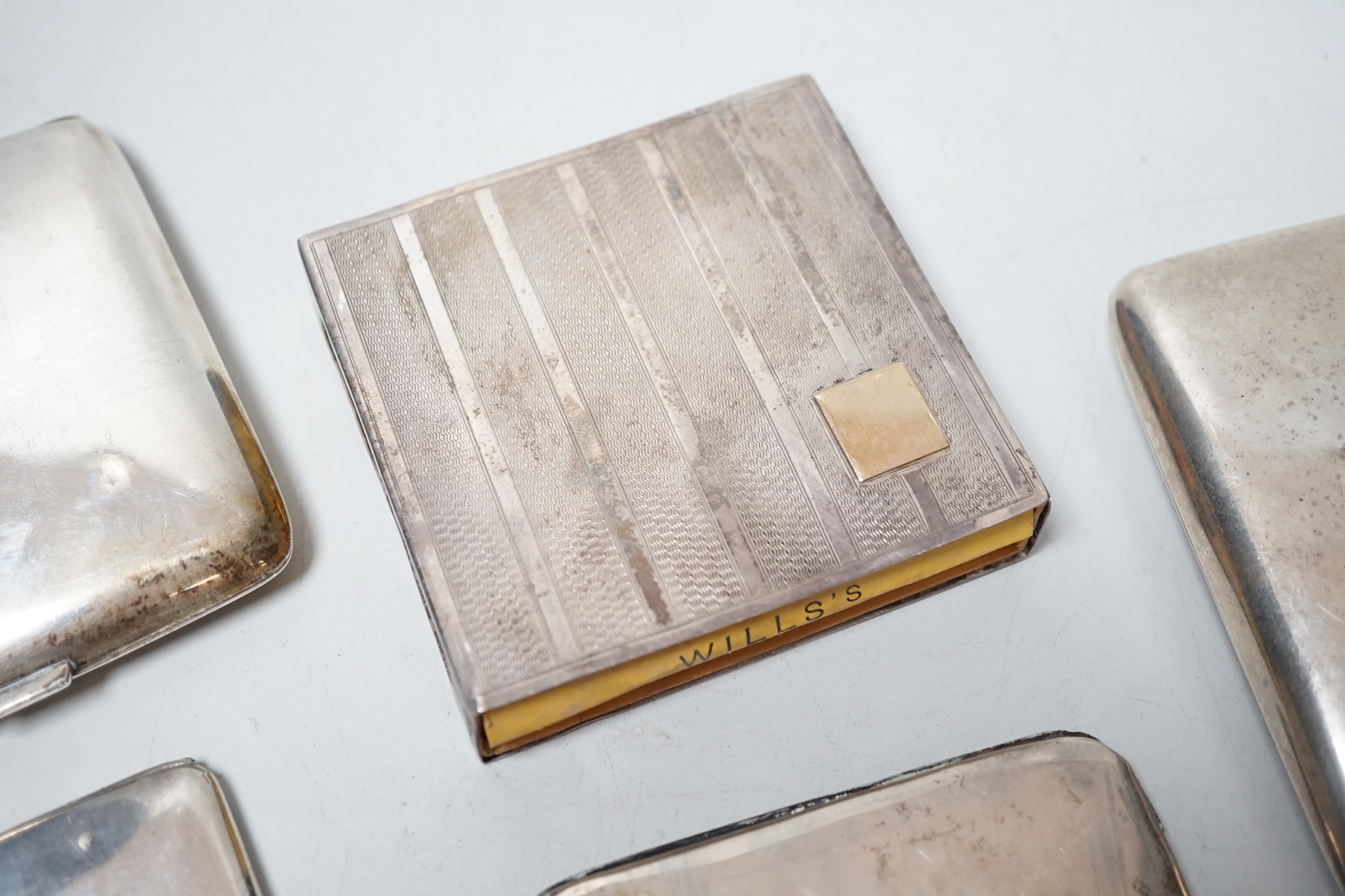 Three assorted silver cigarette cases, a silver tobacco box sleeve and a George V silver travelling pocket watch case with 8 day watch.